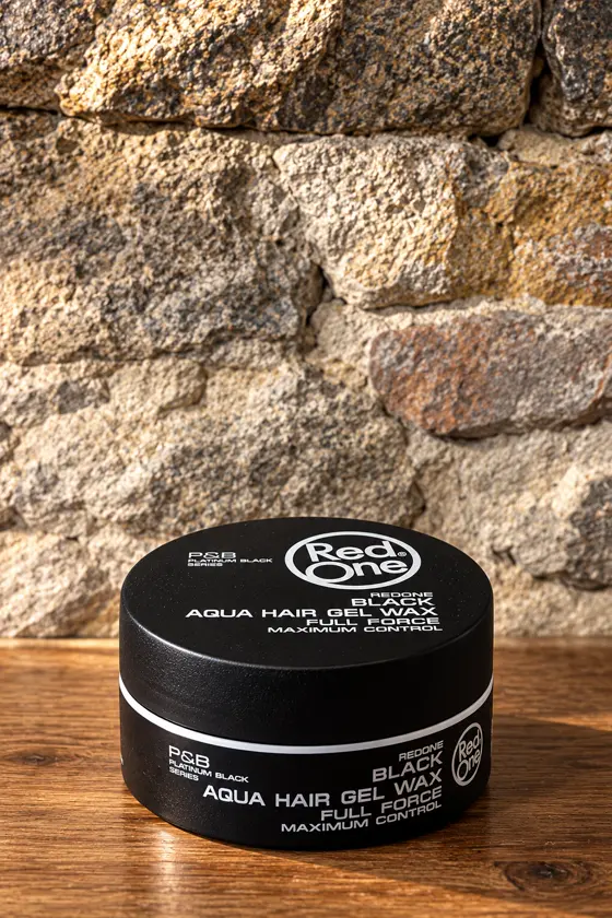 Pot de cire coiffante RedOne Black Aqua Hair Gel Wax, devant le mur en pierre
